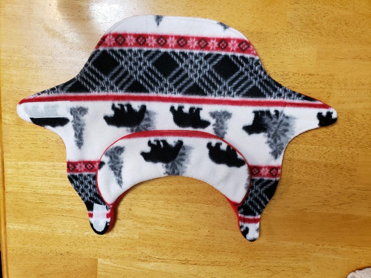 A bear hat with red and black designs on it.