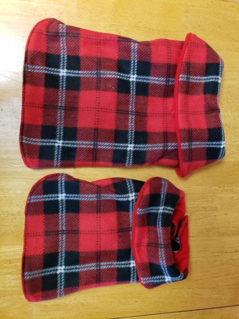 Two red plaid bags on a wooden table.