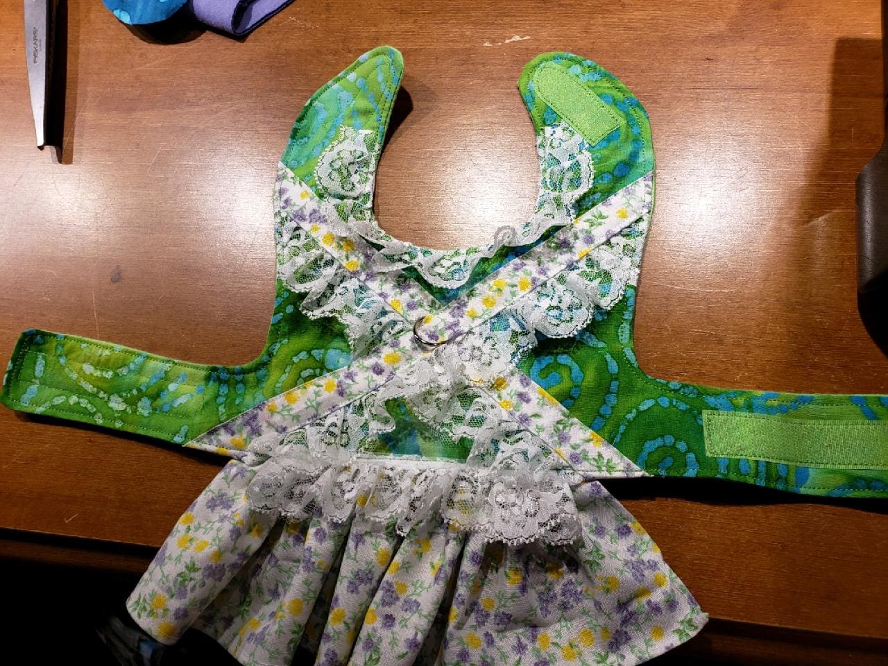 A green dress with flowers on it is sitting on the table.