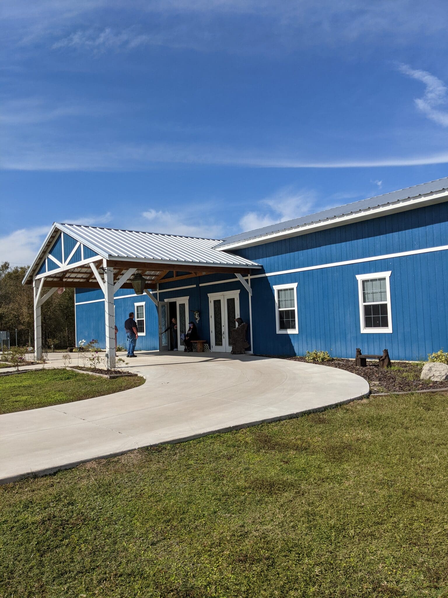 A blue house with a person standing in front of it.