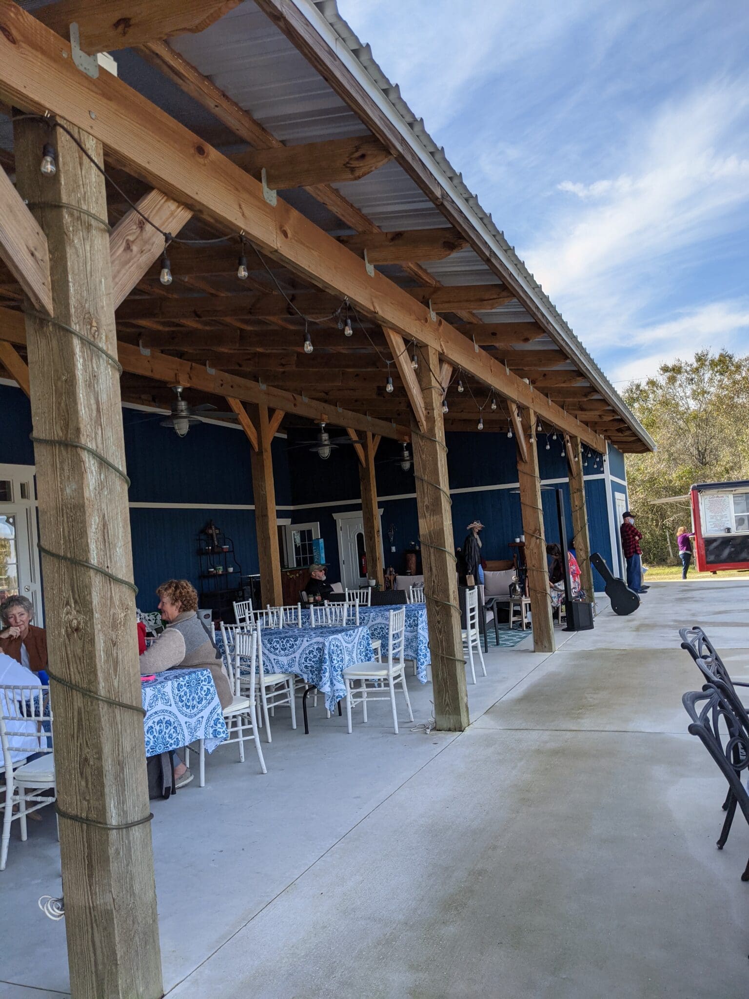 A group of people sitting at tables under an awning.