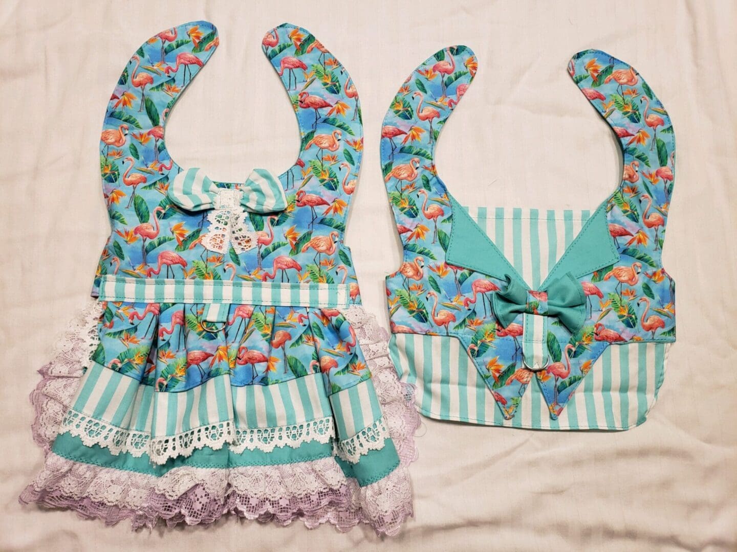 A pair of bibs with bows and lace on them.