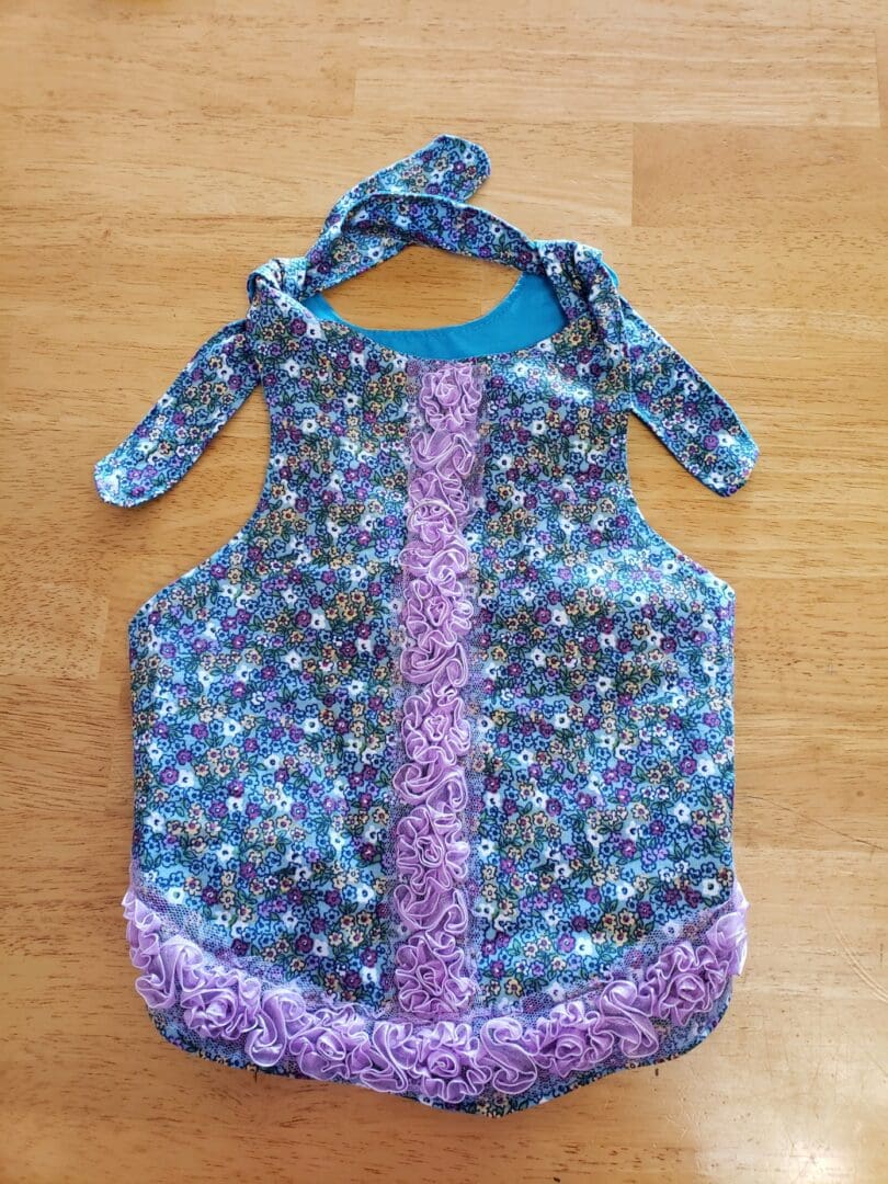 A blue and purple apron with flowers on it.