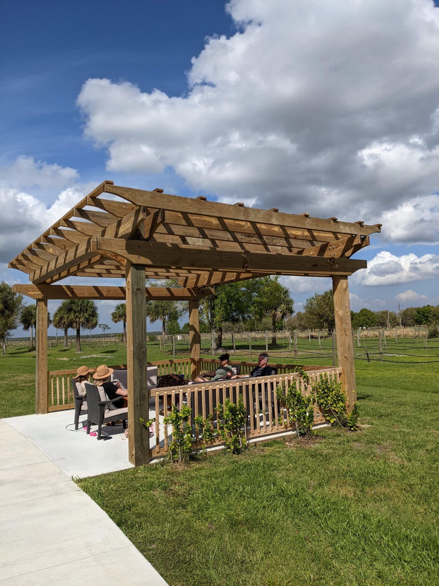 A wooden structure with a bench and chairs on the side.