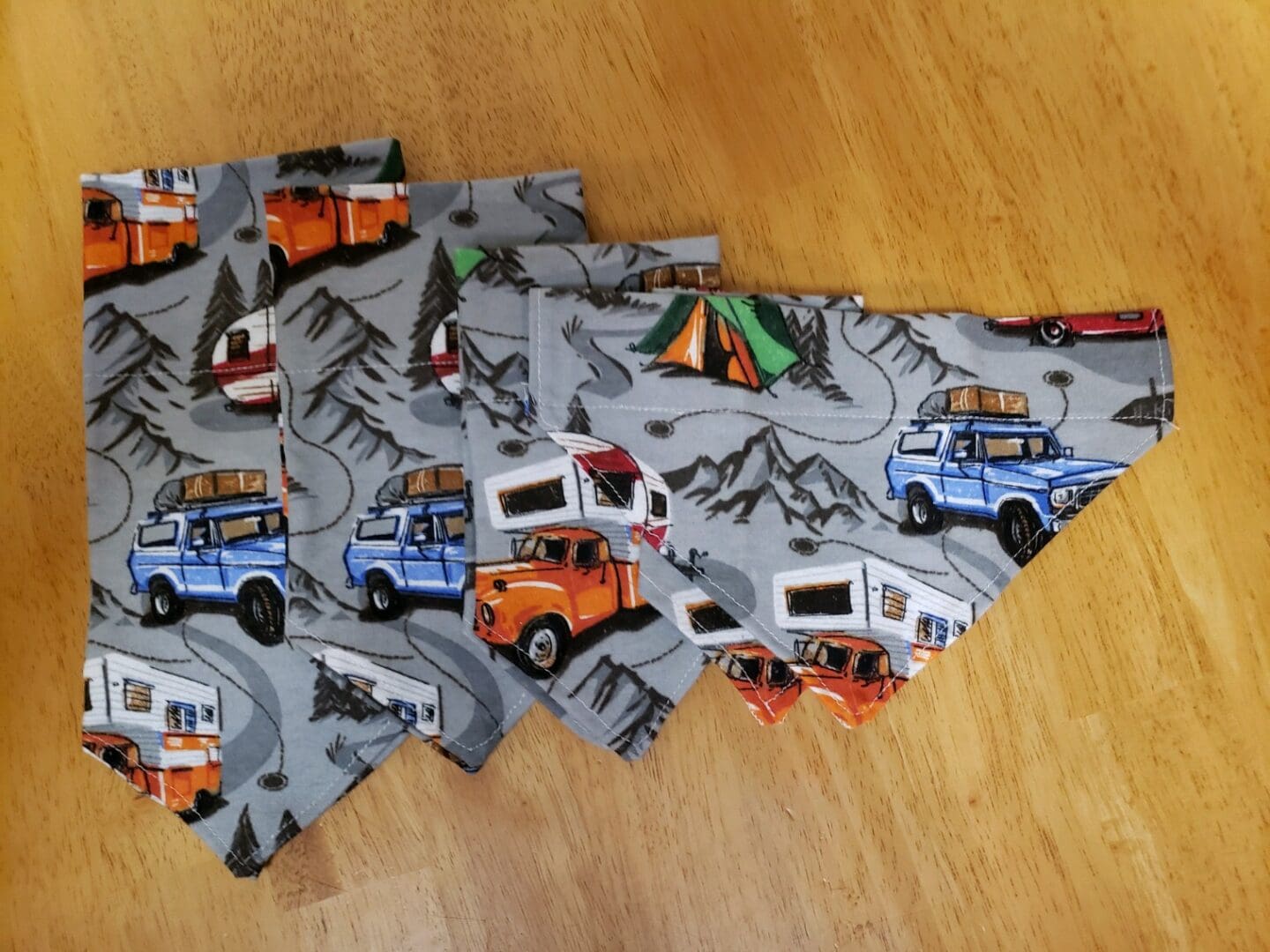 A bunch of folded up dog bandanas with different vehicles on them