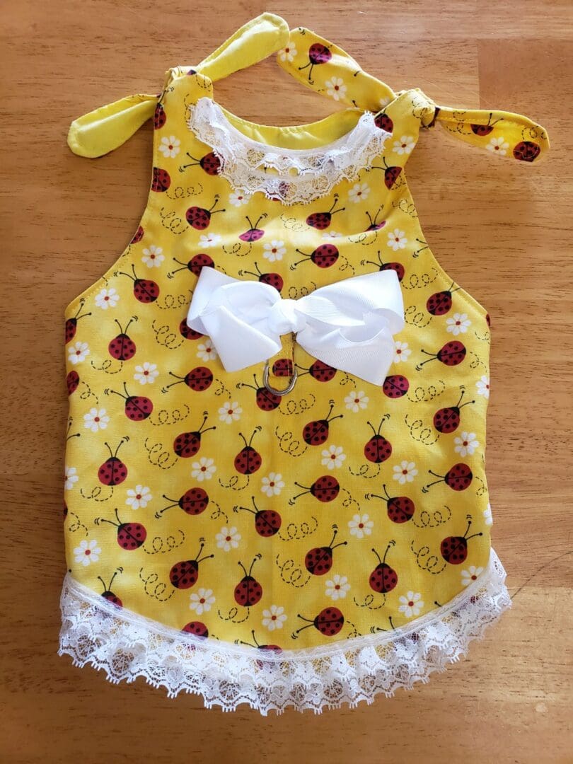 A yellow dress with white bow and flowers on it.