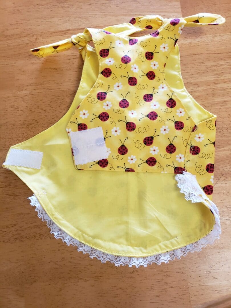 A yellow apron with white lace and red apples.