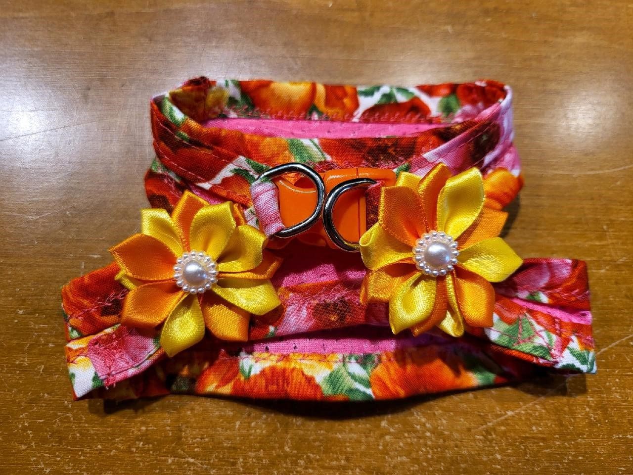 A wooden table with two flowers and scissors on it.