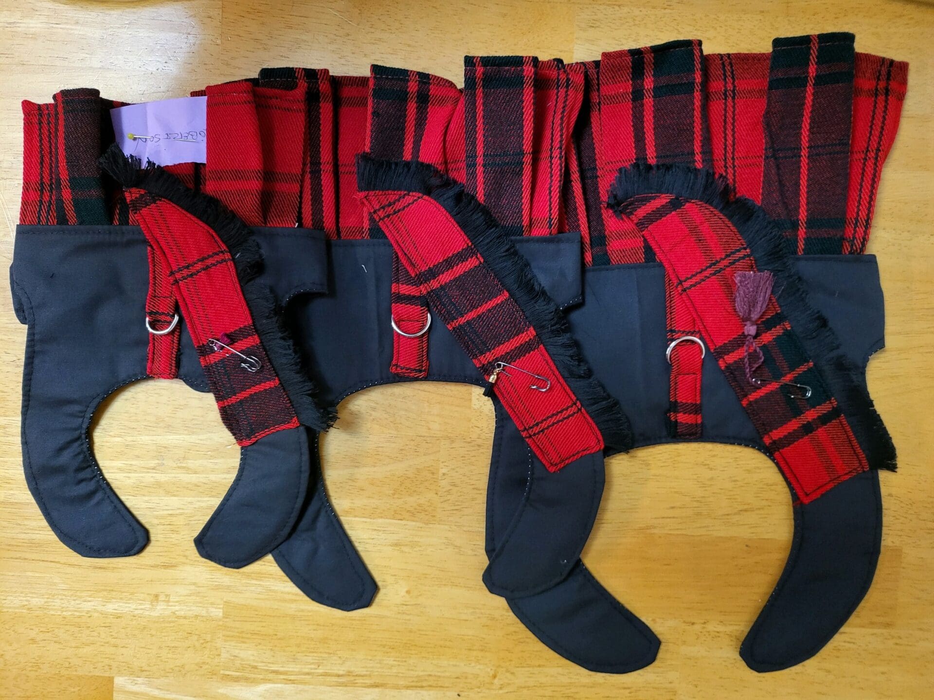 A group of three pairs of legs with red and black plaid stockings.