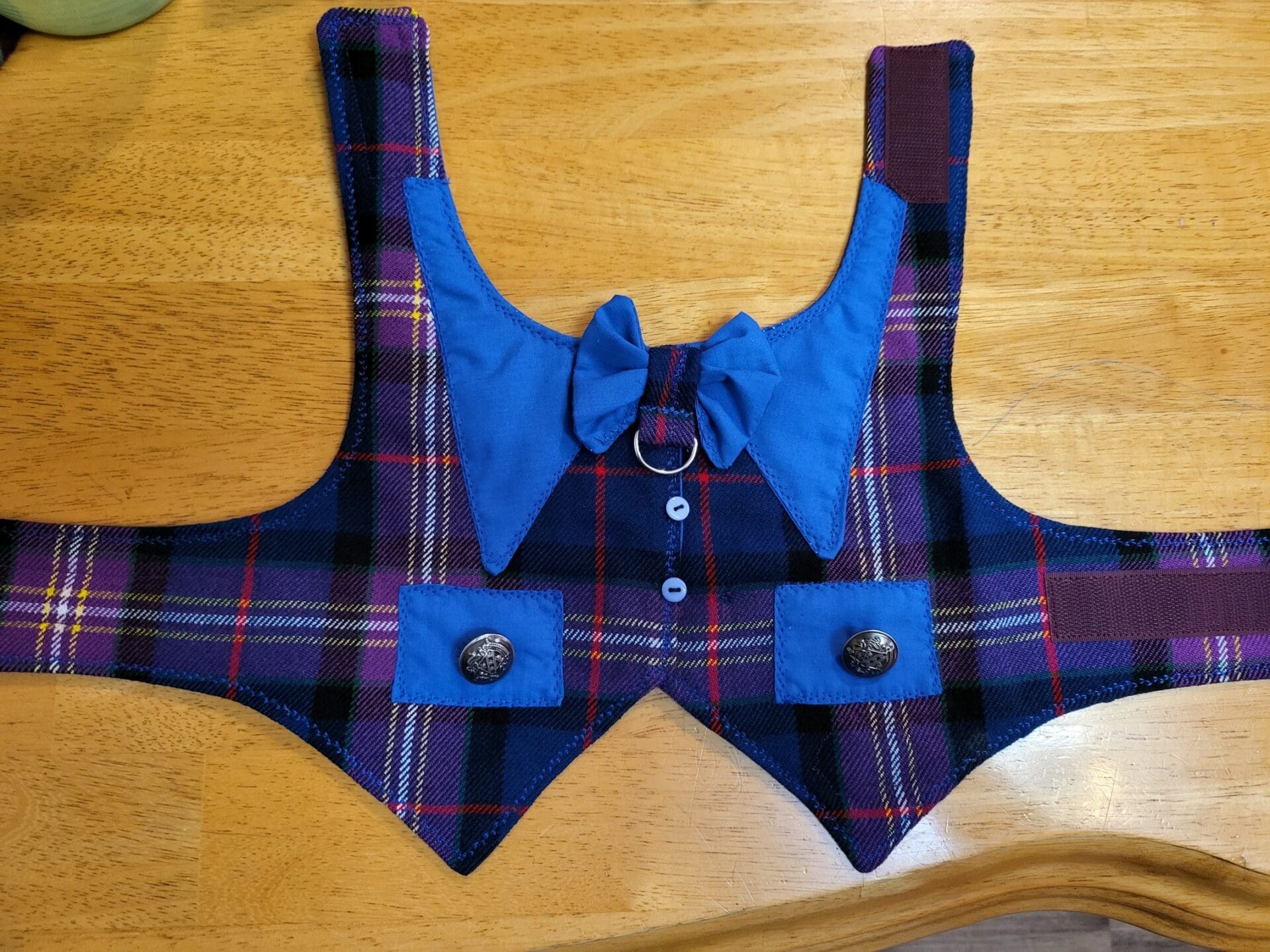 A dog vest with bow tie and buttons on the front.