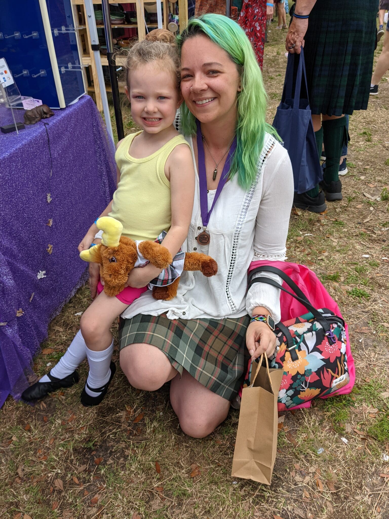 A woman and child sitting on the ground with bags.