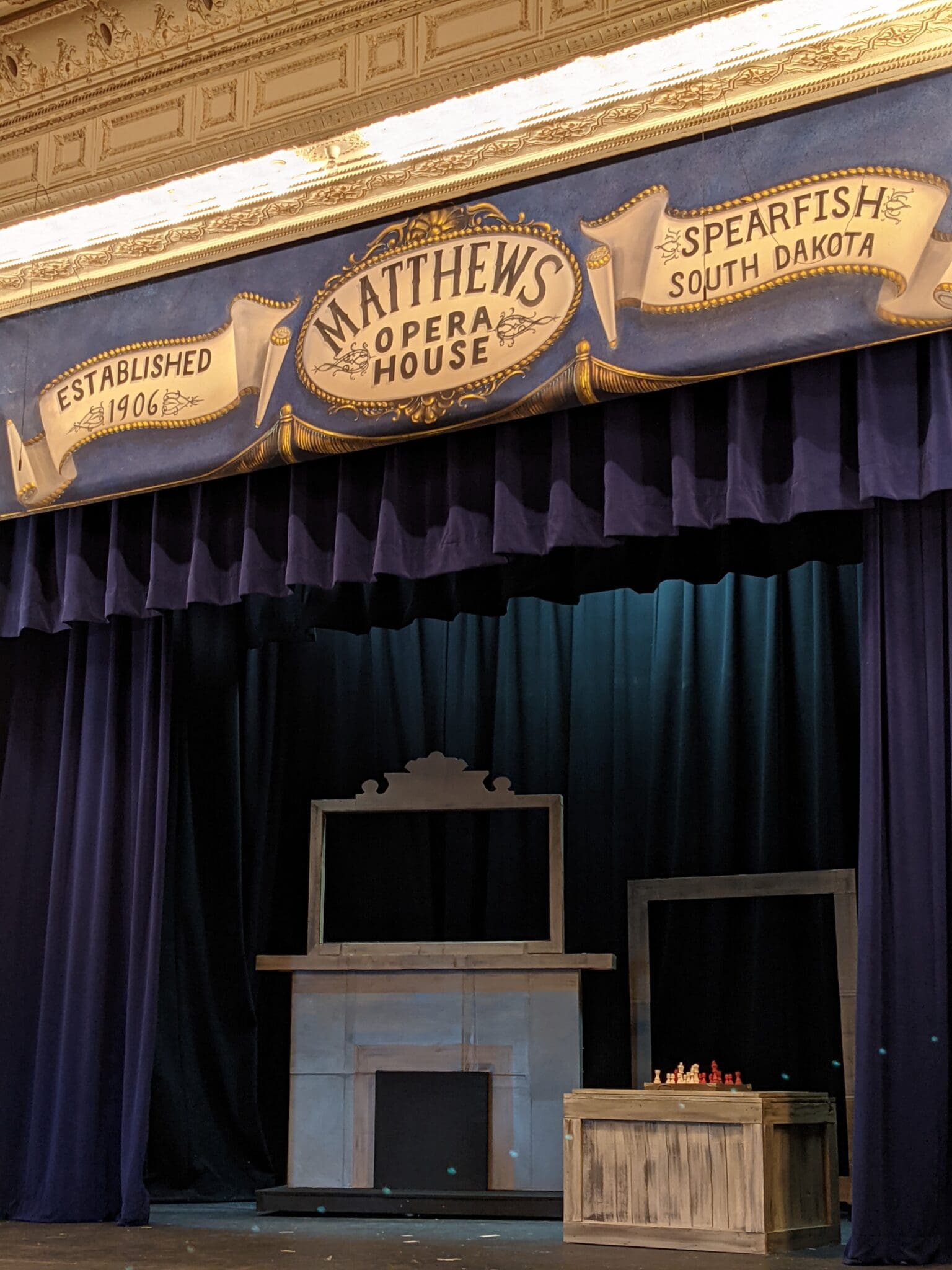 A stage with blue curtains and a fireplace.