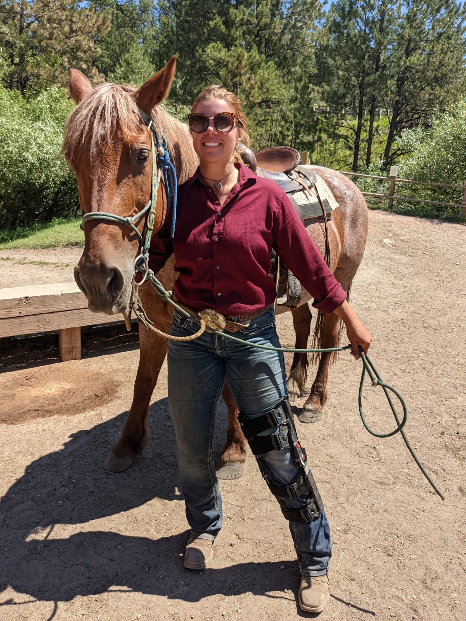 A woman in jeans and boots standing next to a horse.