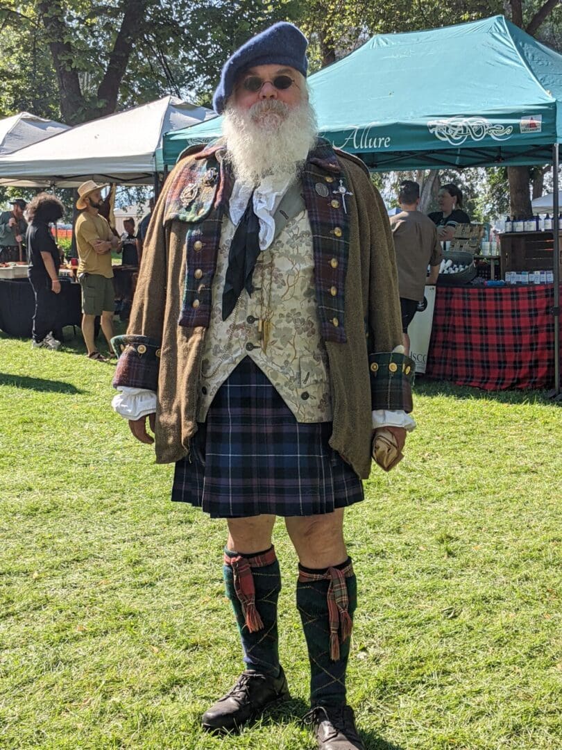 A man in a kilt and boots standing on the grass.