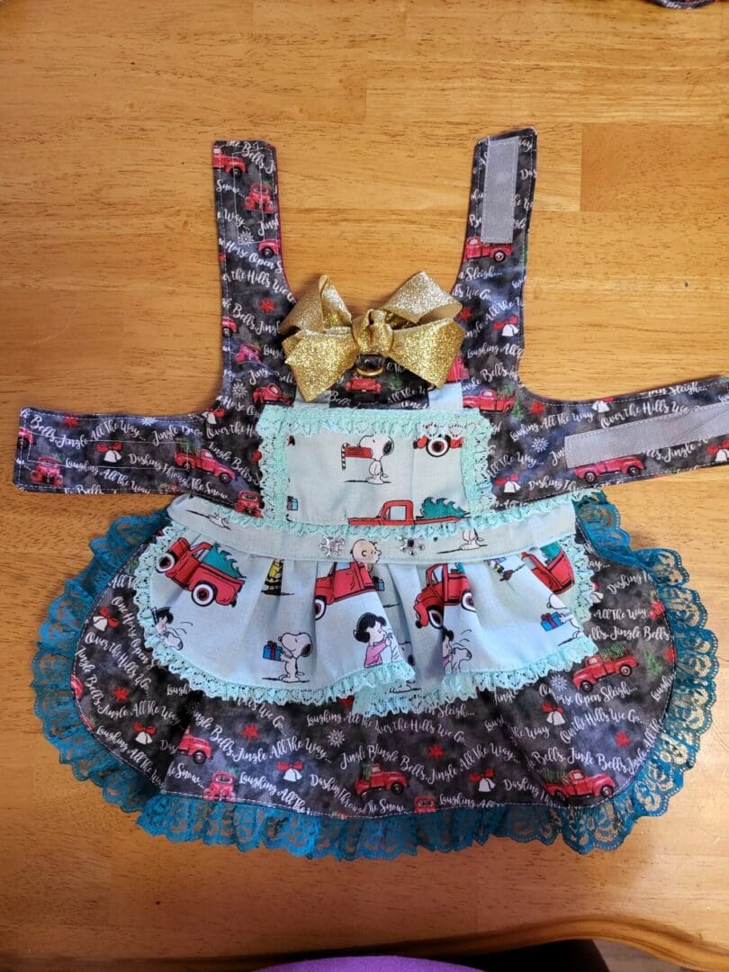 A small dog dress with a bow on top of it.