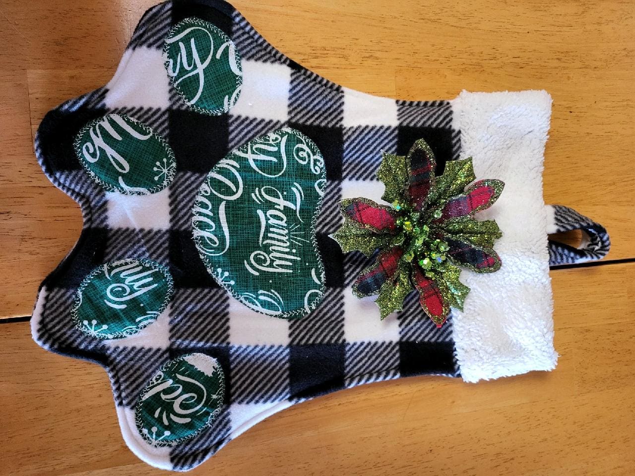 A black and white plaid christmas stocking with a green bow.