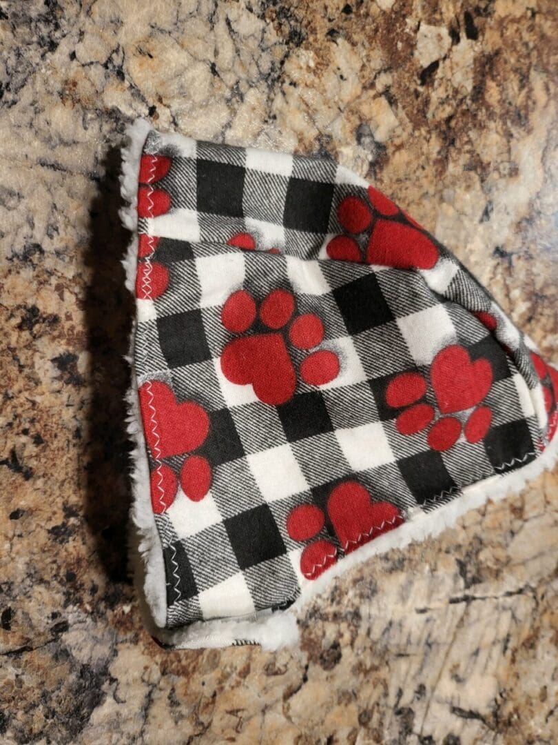 A red and black checkered dog bandana with paw prints.