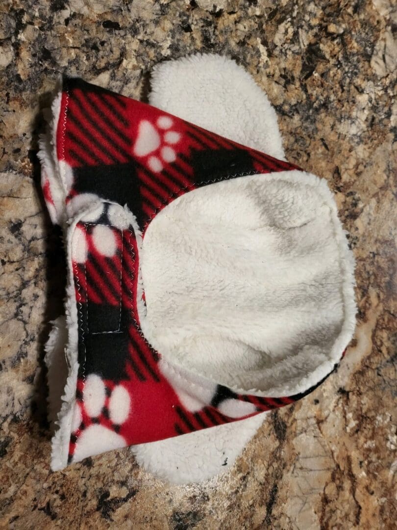 A red and black plaid dog bowl with white paws.