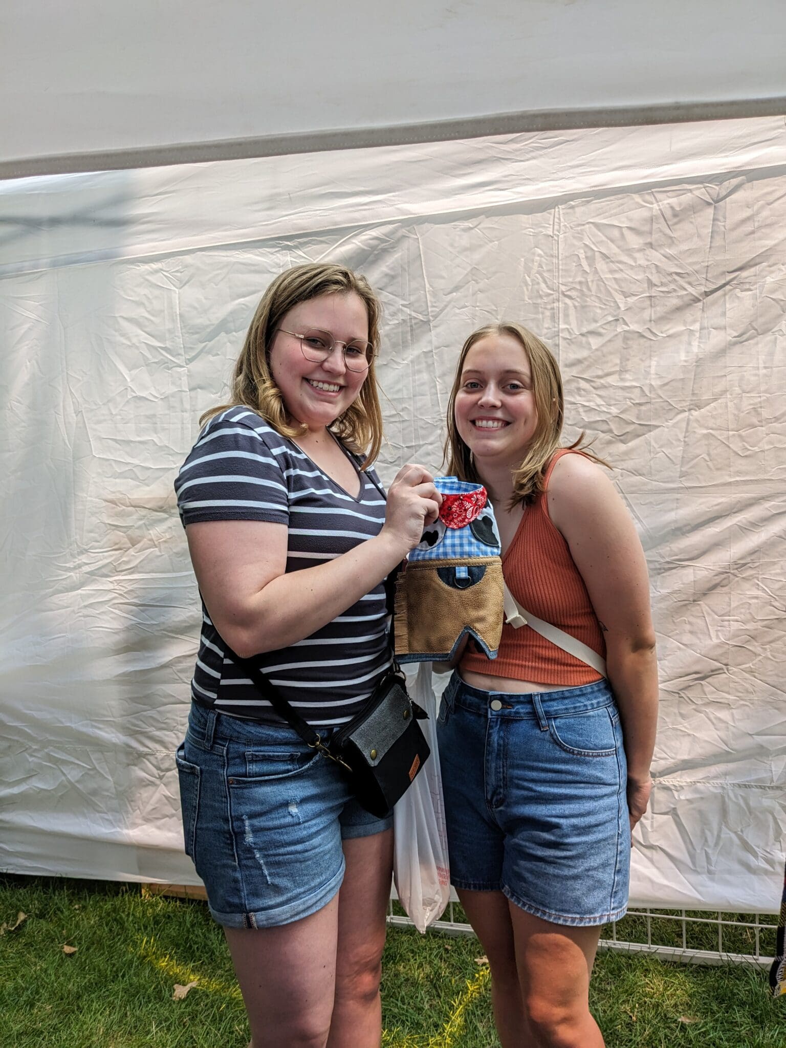 Two women holding a dog in front of a tent.