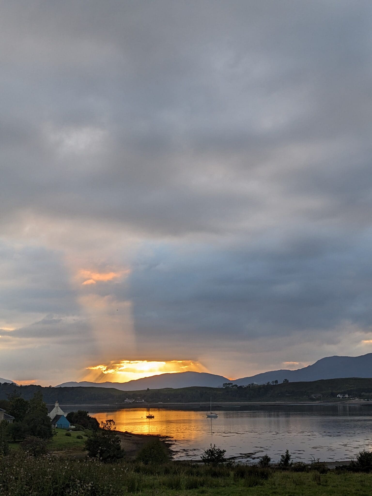 A sunset over the water with mountains in the background.