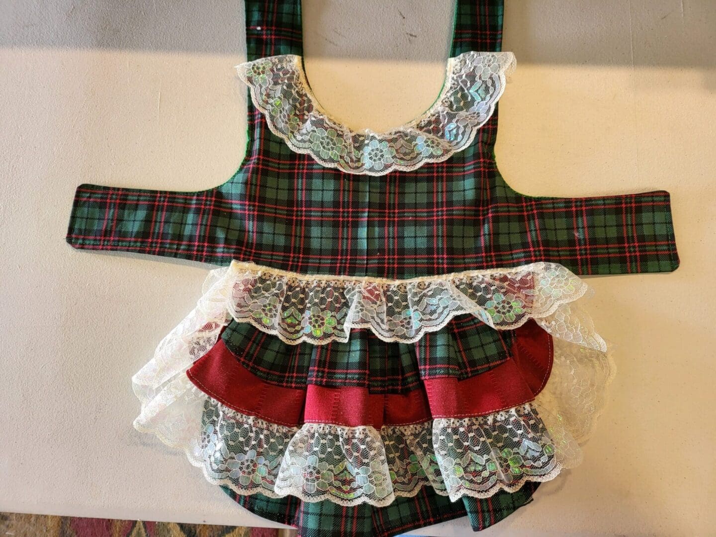 A red and green plaid ruffle diaper cover with lace trim.